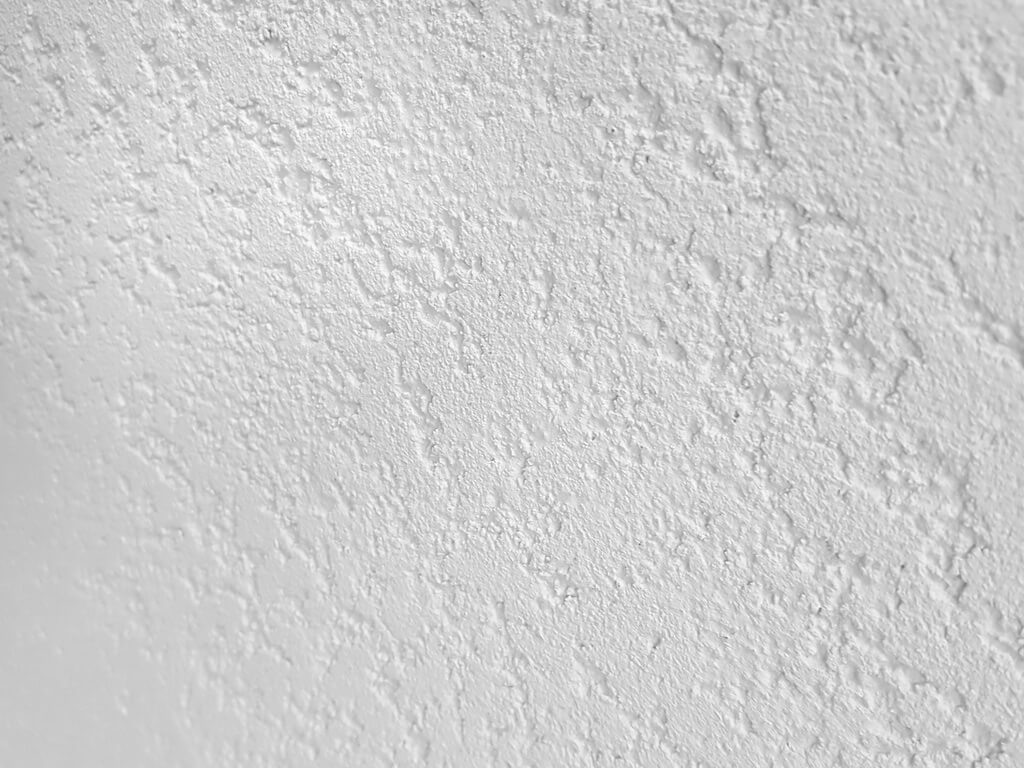 Фактурная штукатурка с мраморной крошкой Алюр Рувидо. Фактурный рисунок Травертин. Базовый белый цвет. Вид вблизи и под углом